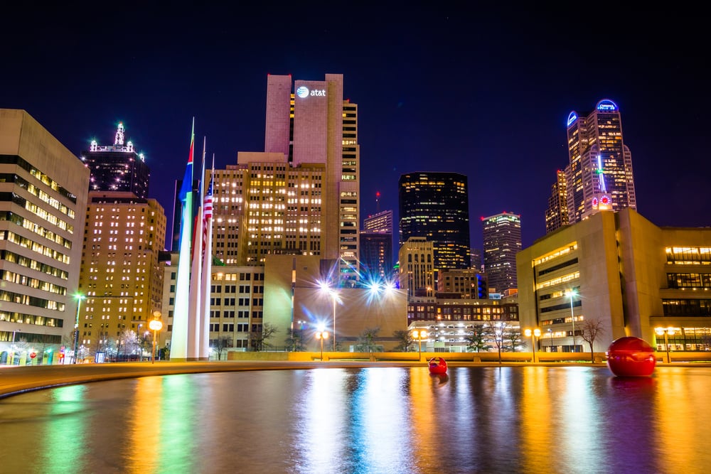 The Dallas skyline and the reflecting pool at City Hall at night, in Dallas, Texas.